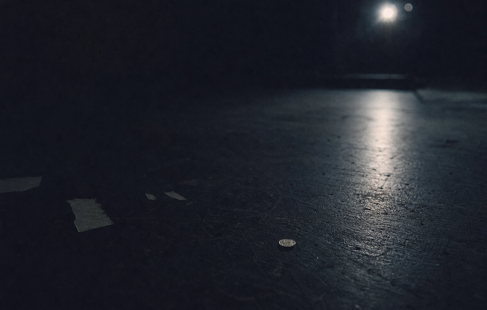 A rough editorial collage of a huge arena reduced to tiny paper cutouts, with a single coin glowing against dark grainy space and scraps of ticket-like shapes scattered around it.